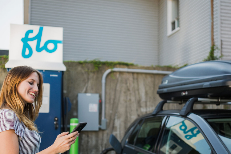 An electric vehicle owner uses a smartphone app to monitor her vehicle's charging.