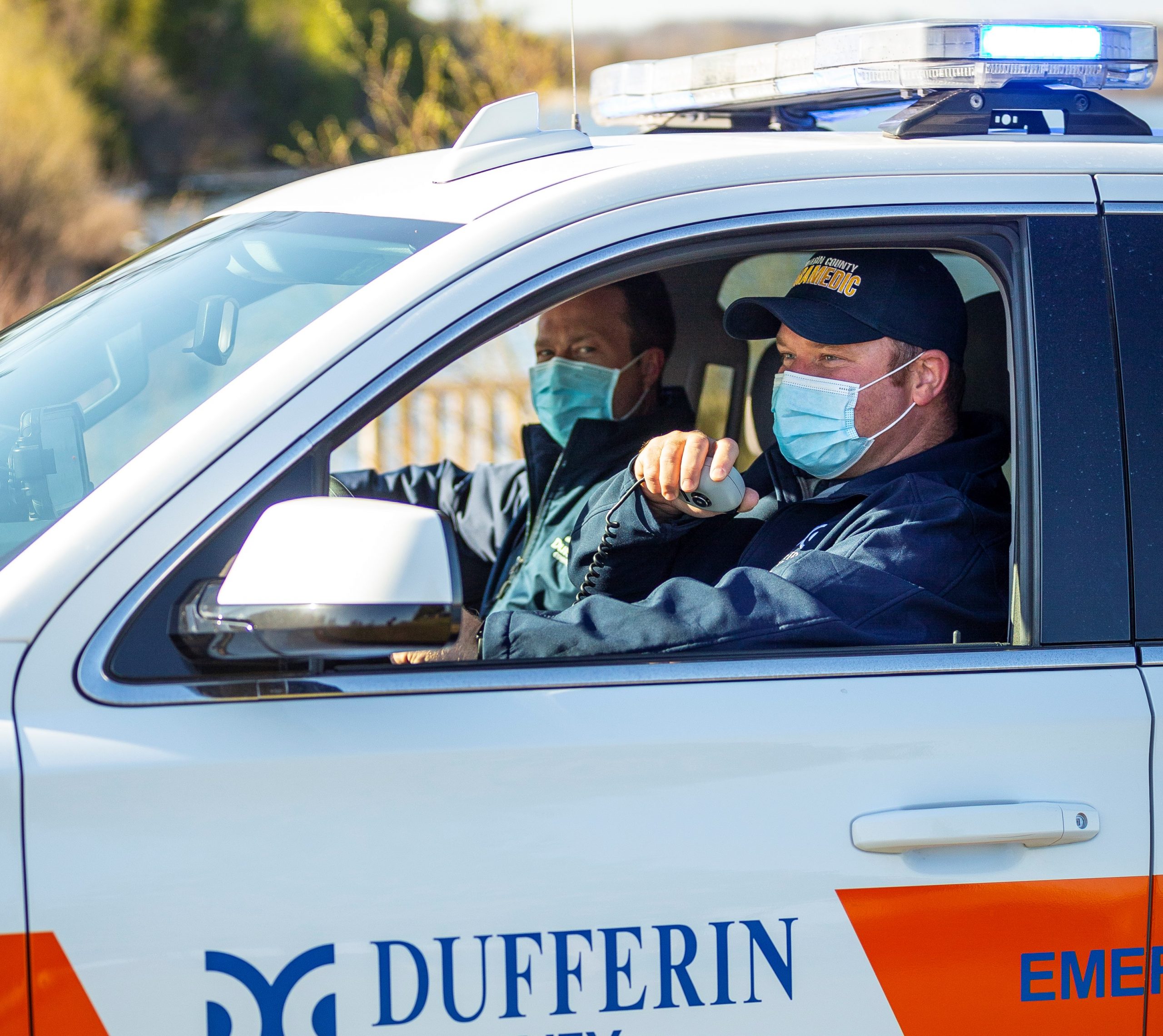 Two men in paramedic uniforms sitting in the front of an SUV