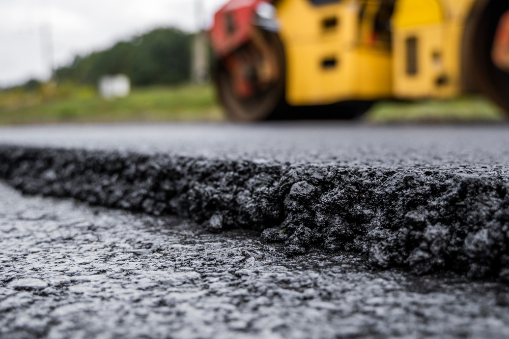 A closeup of road asphalt with a steam roller.