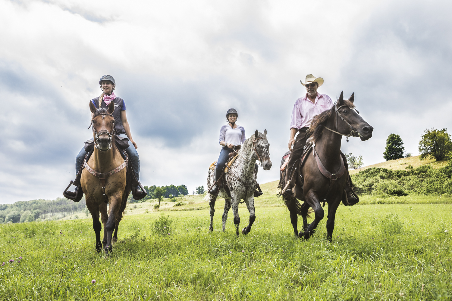 Three people ride horseback in an open field in Dufferin County.