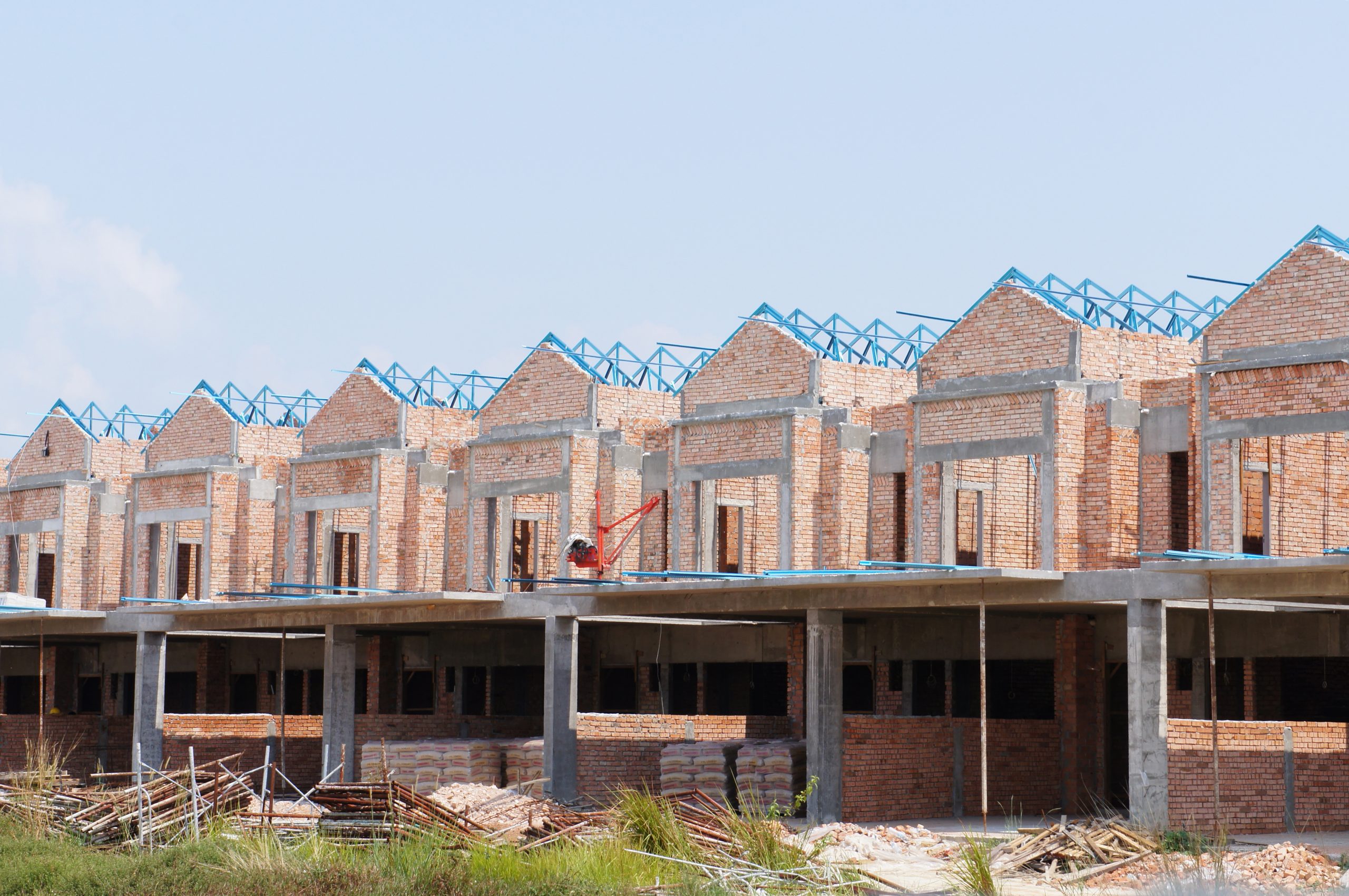 A row of residential dwellings are being constructed with a blue sky above