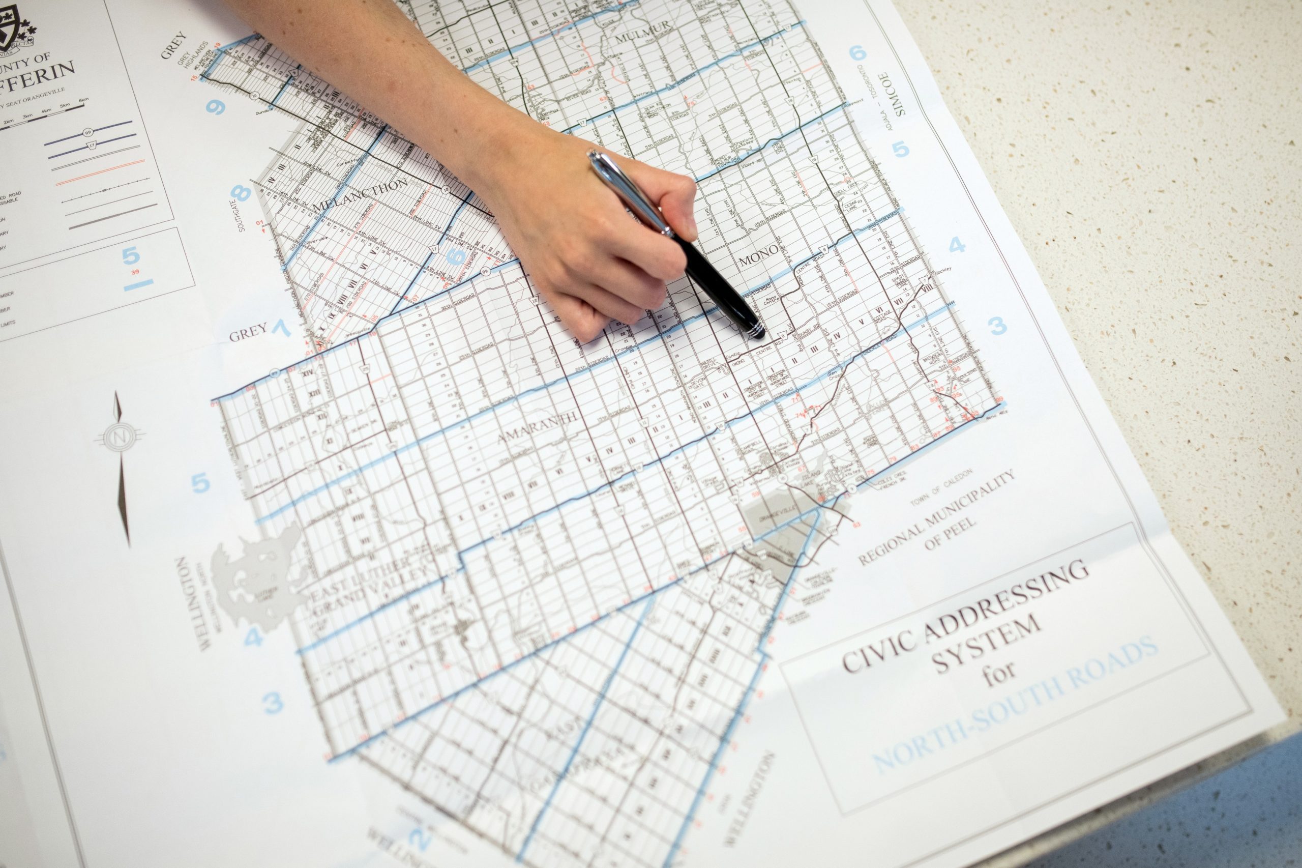 A hand uses a pen to point to a road on a Civic Addressing System for North-South Roads in Dufferin County