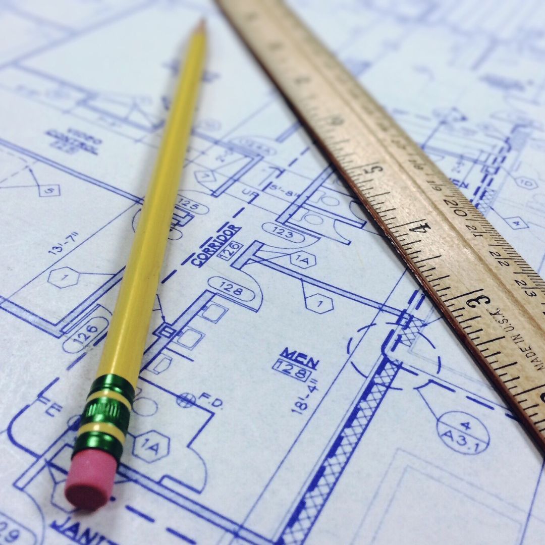 Pencil and ruler sitting on top of a blueprint