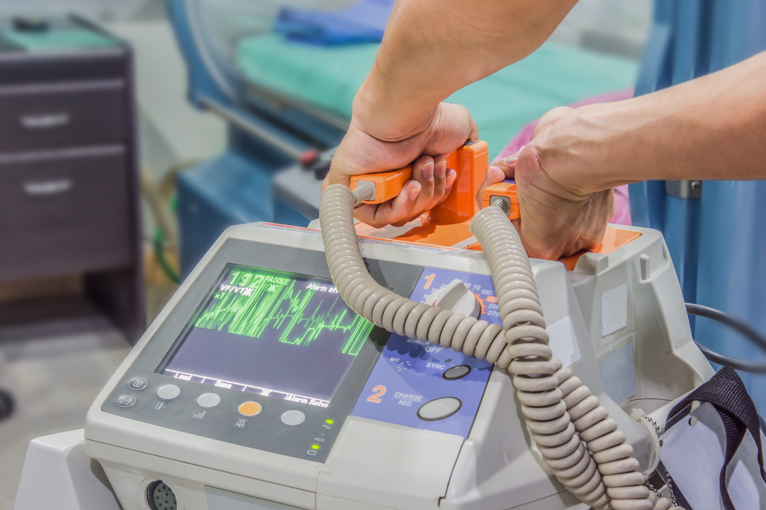 A person charges a defibrillator machine to prepare for use.