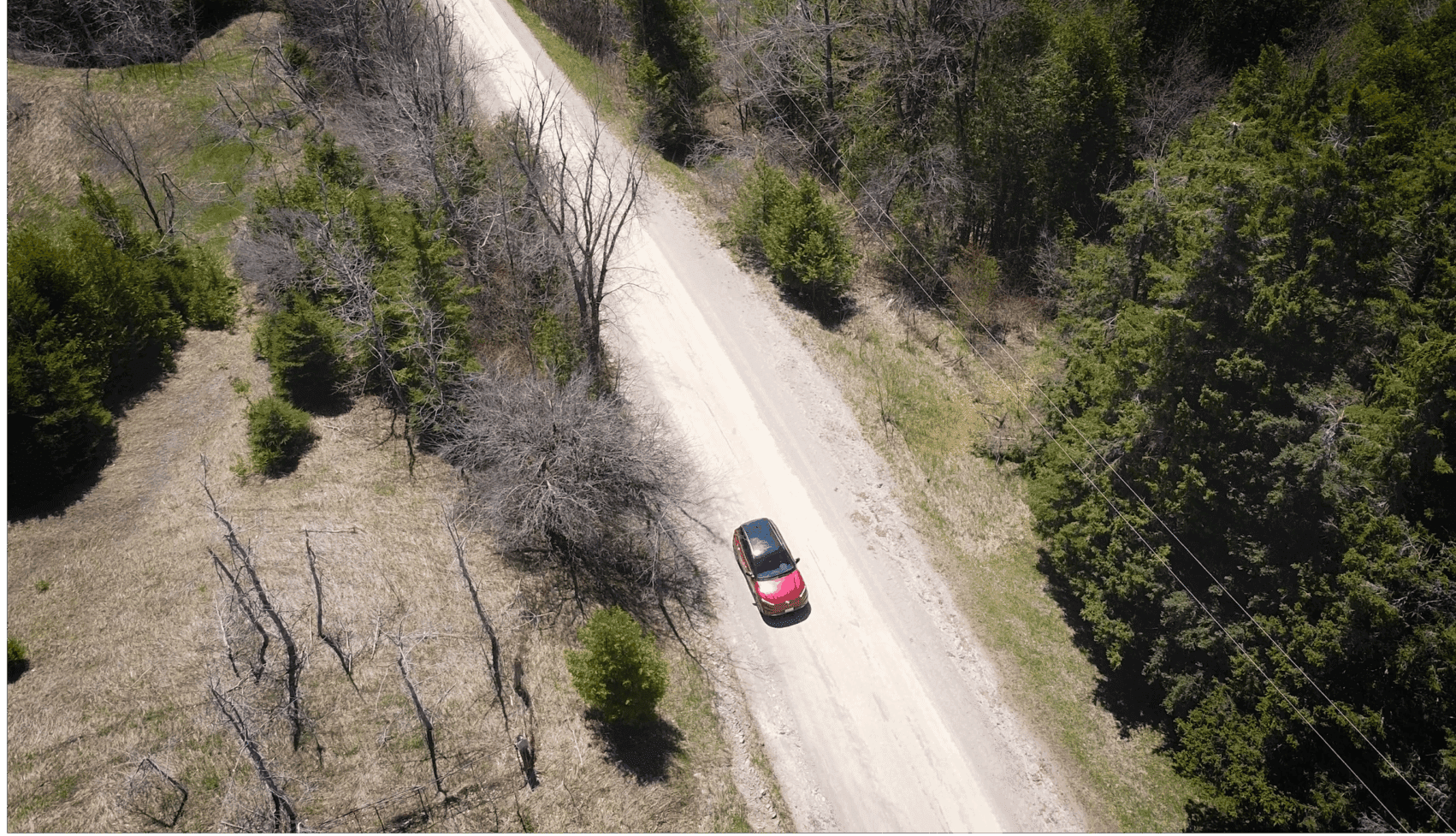 A red electric SUV drives along a gravel road