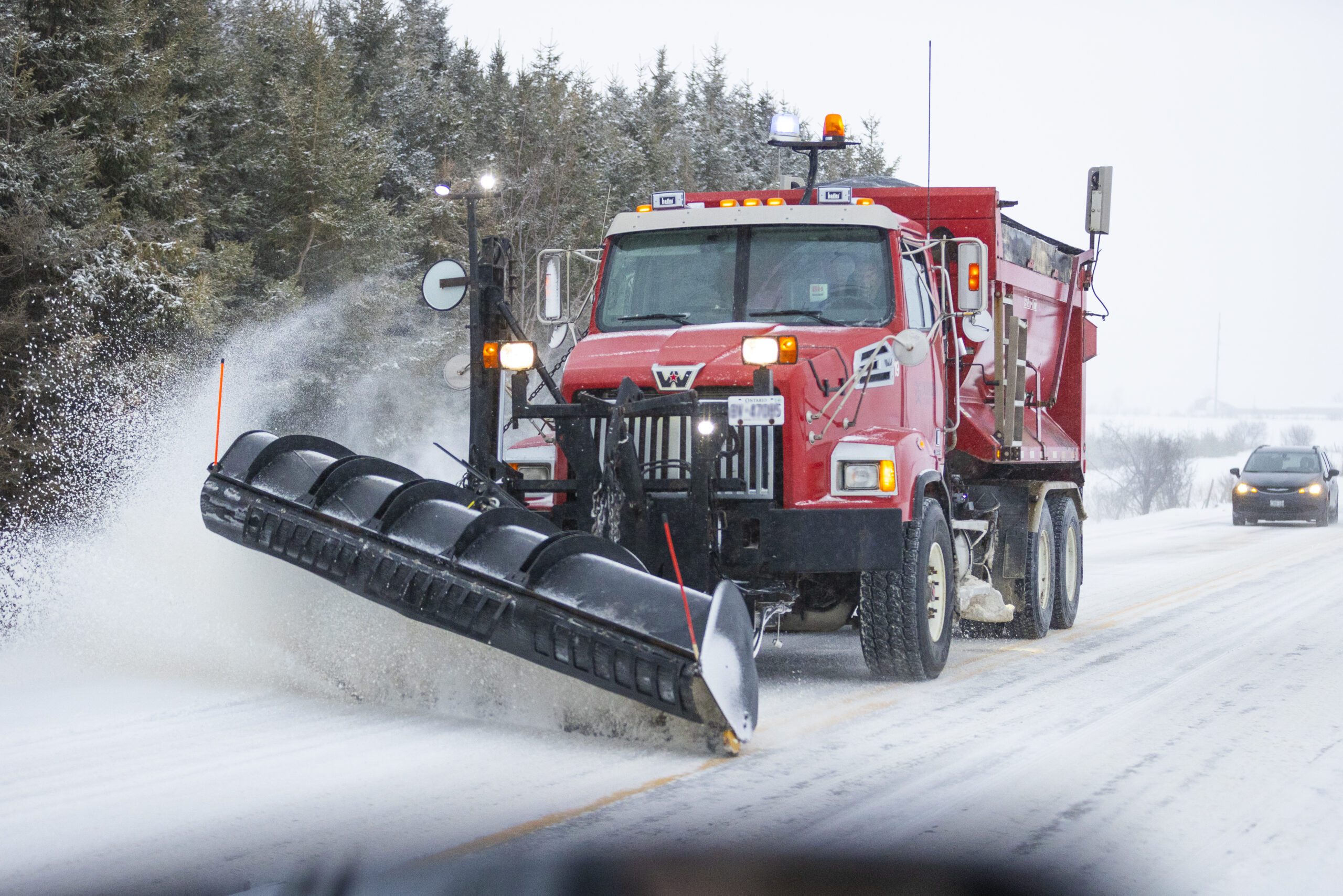 Dufferin County red snow plow clearing snow off road.