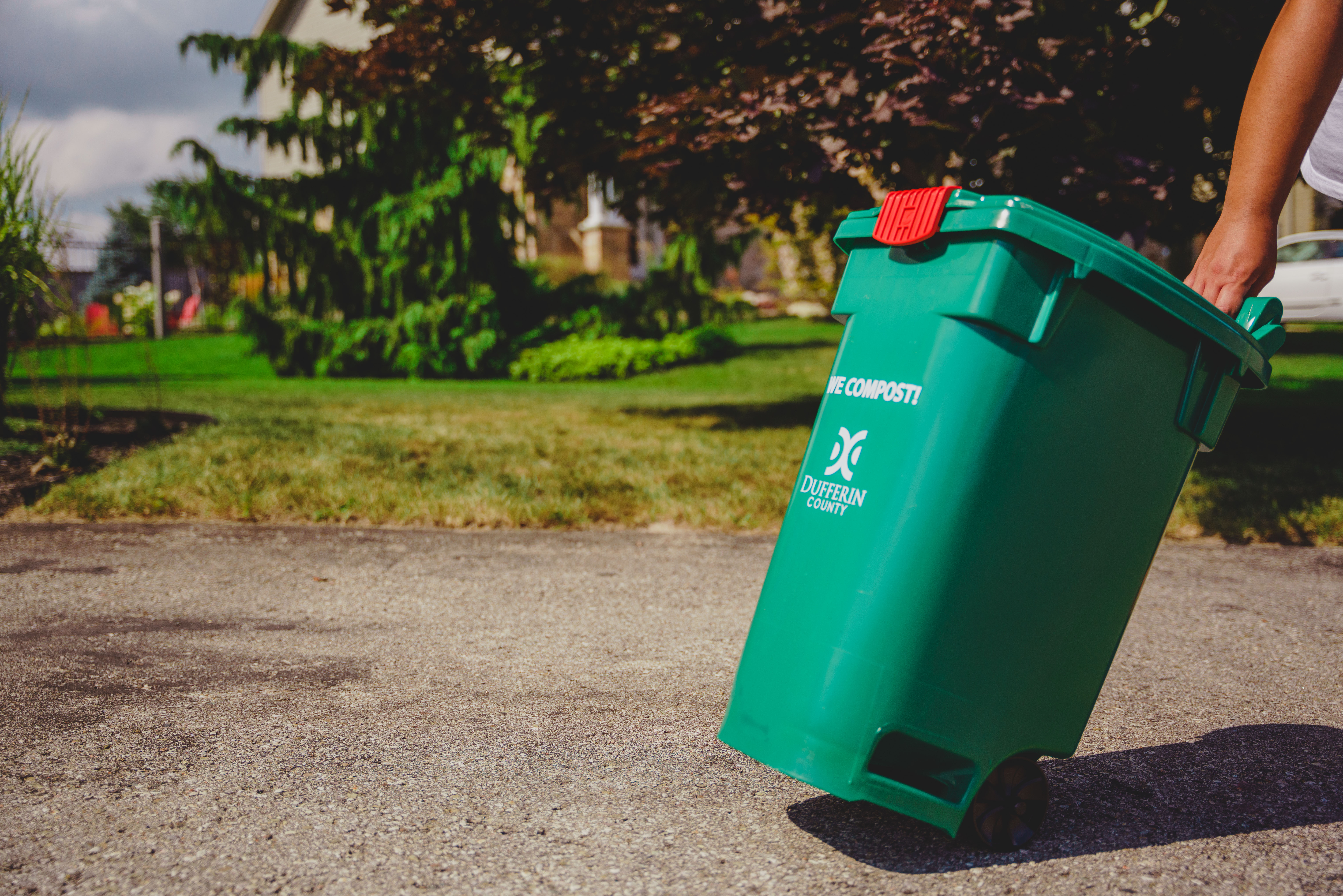 Green bin being carried on pavement