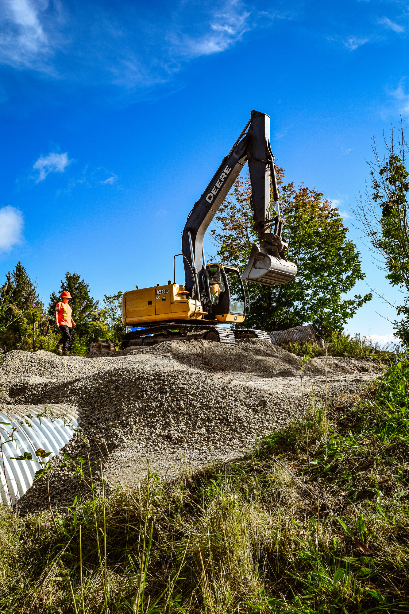 Construction machinery in field with sunny sky behind.